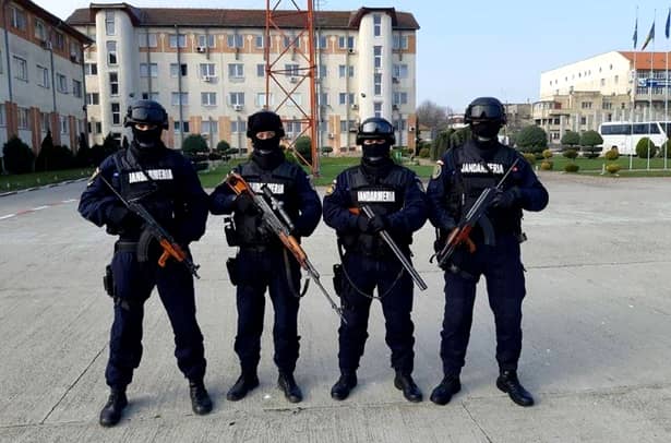 Patru reprezentanţi ai Jandarmeriei Române, fotografiaţi cu armele la piept