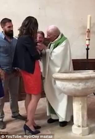 Preotul încercând să-l liniștească, în timp ce mama lui se sperie de acesta și de cum reacționează bebelușul